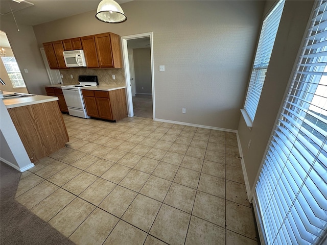 kitchen with light tile patterned floors, white appliances, light countertops, decorative backsplash, and brown cabinetry