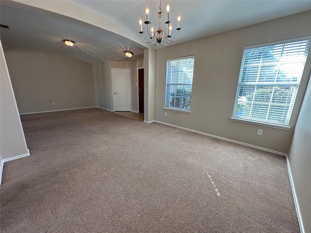 carpeted spare room with baseboards, lofted ceiling, and an inviting chandelier