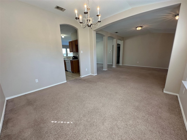 empty room featuring light carpet, visible vents, arched walkways, and a notable chandelier