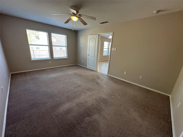 carpeted spare room featuring visible vents, plenty of natural light, baseboards, and ceiling fan