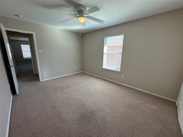 empty room featuring light colored carpet, ceiling fan, and baseboards