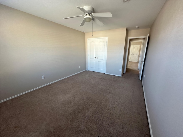 unfurnished bedroom featuring a closet, dark carpet, baseboards, and ceiling fan