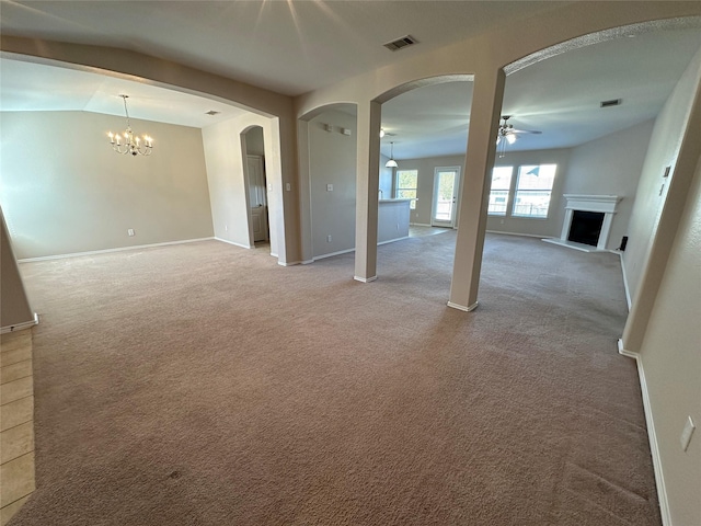 spare room featuring a fireplace with raised hearth, ceiling fan with notable chandelier, visible vents, and light colored carpet