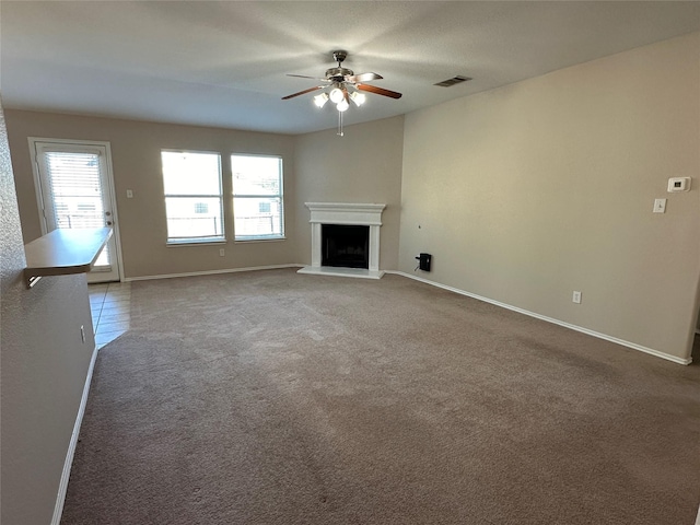 unfurnished living room with a fireplace with raised hearth, carpet flooring, a ceiling fan, visible vents, and baseboards