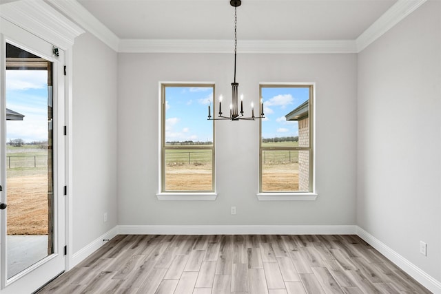 unfurnished dining area with a notable chandelier, light wood-style flooring, baseboards, and a wealth of natural light