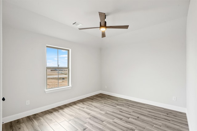 spare room featuring light wood finished floors, visible vents, baseboards, and a ceiling fan