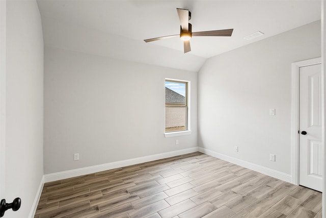 empty room with wood finished floors, visible vents, a ceiling fan, vaulted ceiling, and baseboards