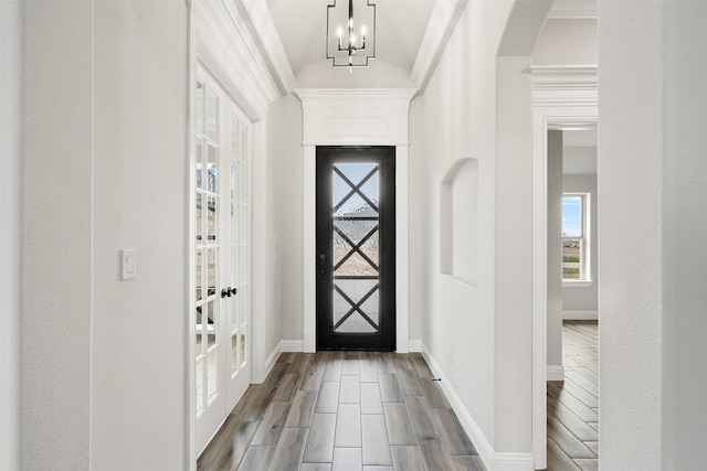 entryway with arched walkways, french doors, wood finished floors, and baseboards