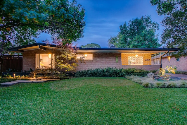 view of front of house featuring a yard and brick siding