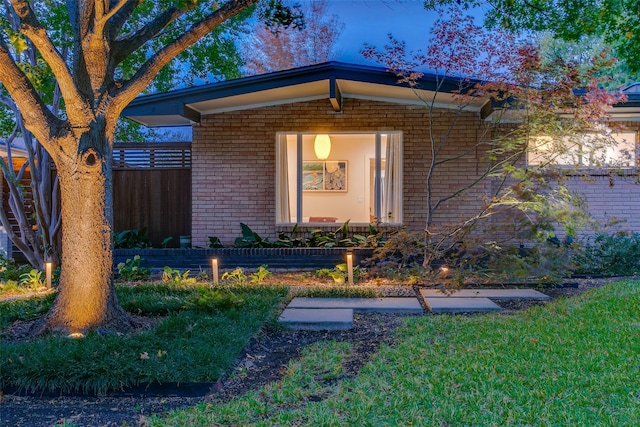 entrance to property featuring brick siding and fence