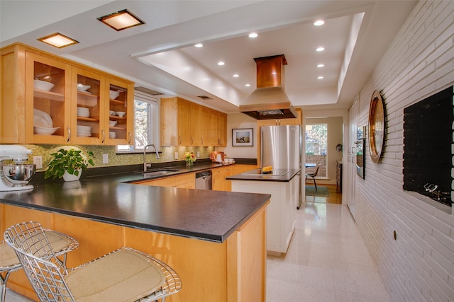 kitchen with dark countertops, glass insert cabinets, island exhaust hood, stainless steel appliances, and a kitchen bar