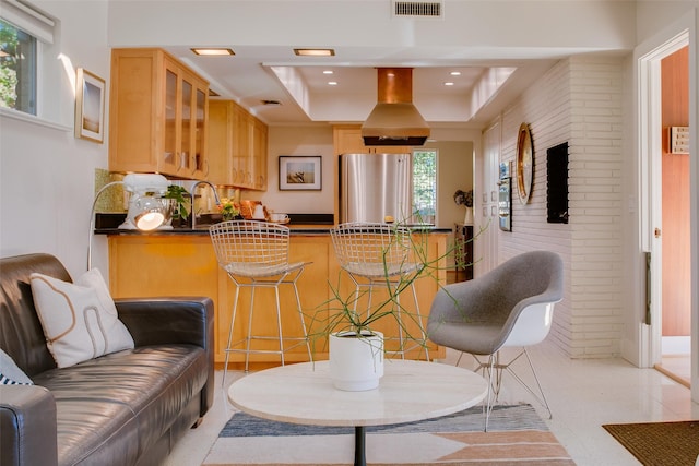 kitchen featuring dark countertops, visible vents, freestanding refrigerator, island range hood, and a peninsula