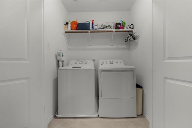 clothes washing area featuring laundry area, washing machine and dryer, and light tile patterned floors