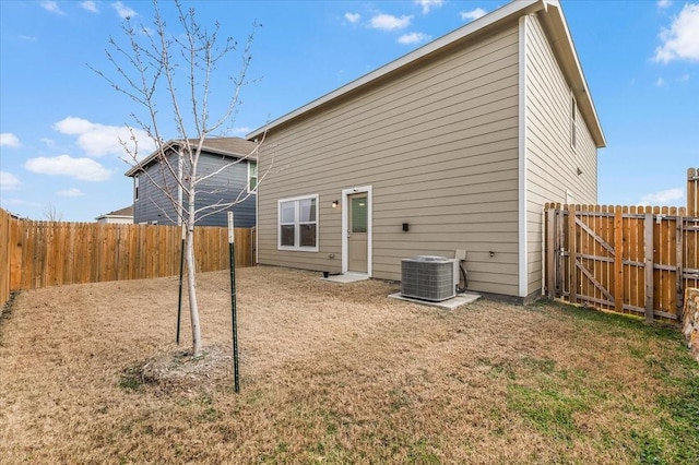 rear view of house featuring a fenced backyard, a lawn, and central AC unit