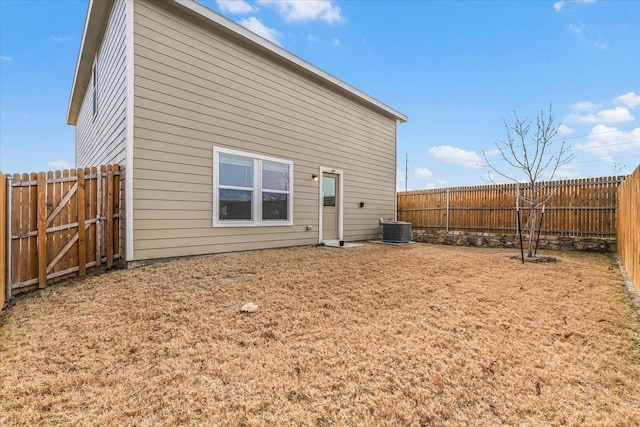 rear view of house featuring a yard, a fenced backyard, and central air condition unit