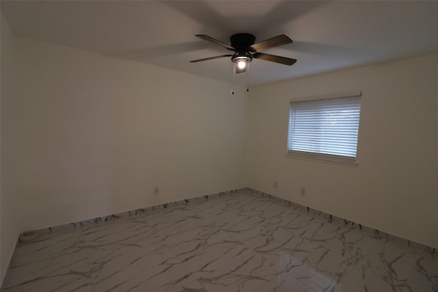 empty room featuring marble finish floor, baseboards, and a ceiling fan