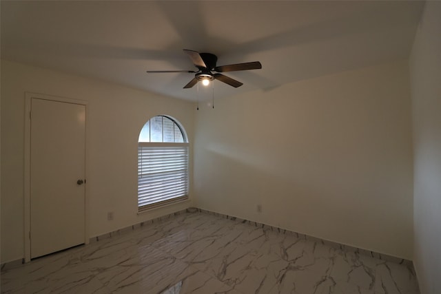 empty room featuring ceiling fan and marble finish floor