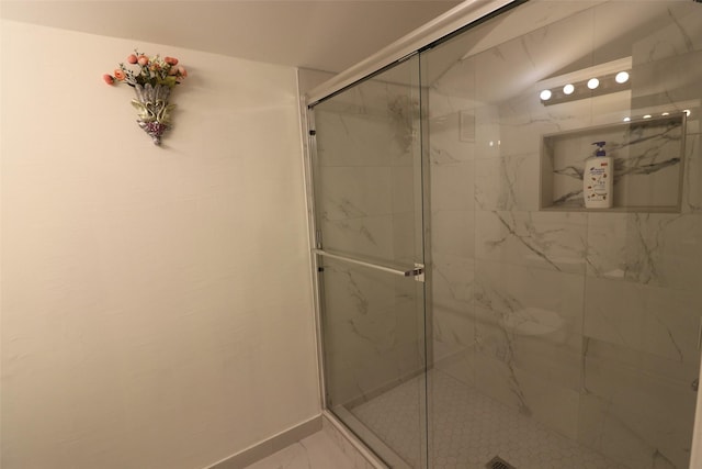 bathroom with a marble finish shower and baseboards