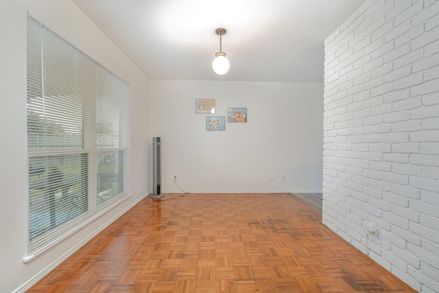 unfurnished room with baseboards and brick wall