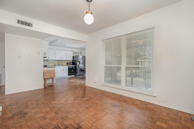 unfurnished living room featuring a sink, visible vents, and baseboards