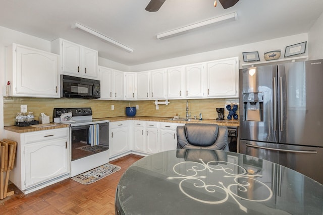 kitchen featuring black microwave, stainless steel fridge, white electric range, white cabinetry, and a sink