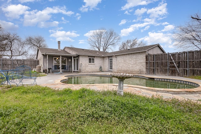 back of property featuring brick siding, a patio area, a fenced backyard, and a fenced in pool