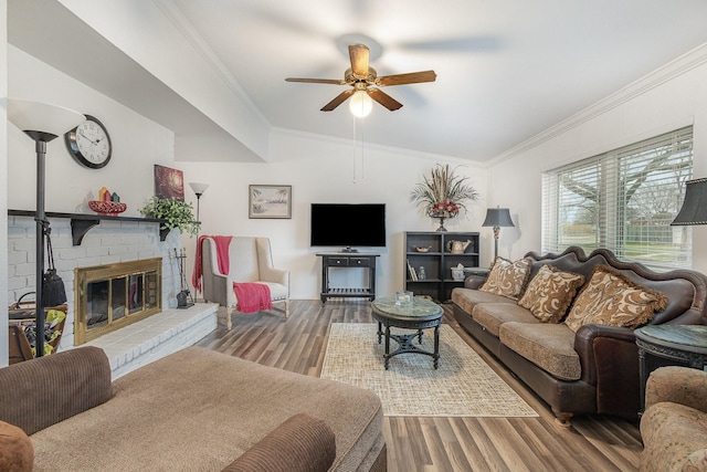 living area with a brick fireplace, ornamental molding, and wood finished floors