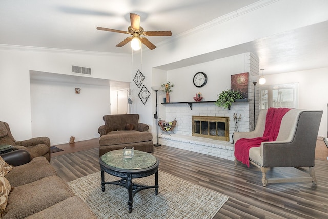 living area with visible vents, a ceiling fan, wood finished floors, crown molding, and a fireplace