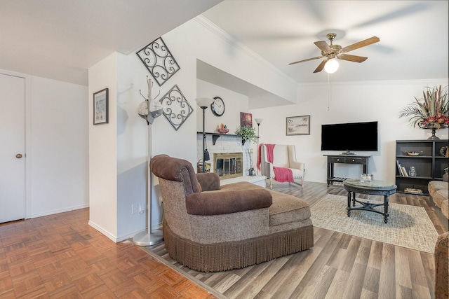 living room with a fireplace, a ceiling fan, baseboards, parquet floors, and ornamental molding