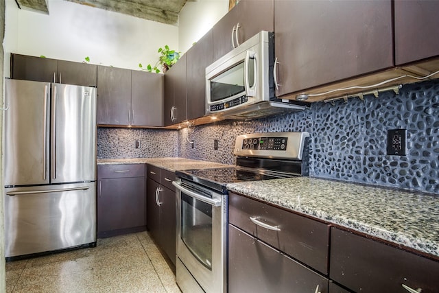 kitchen with light speckled floor, stone counters, dark brown cabinetry, stainless steel appliances, and decorative backsplash