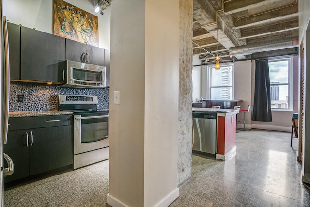 kitchen featuring baseboards, appliances with stainless steel finishes, light speckled floor, and backsplash