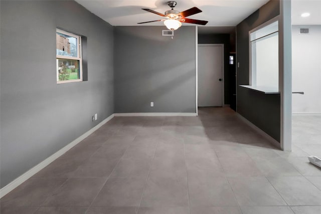 unfurnished room with baseboards, visible vents, and ceiling fan