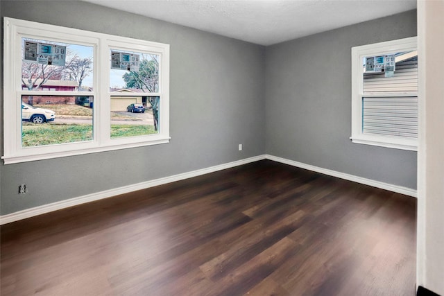 spare room featuring dark wood-type flooring and baseboards