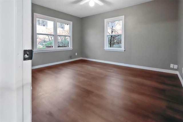 spare room featuring dark wood-style flooring and baseboards