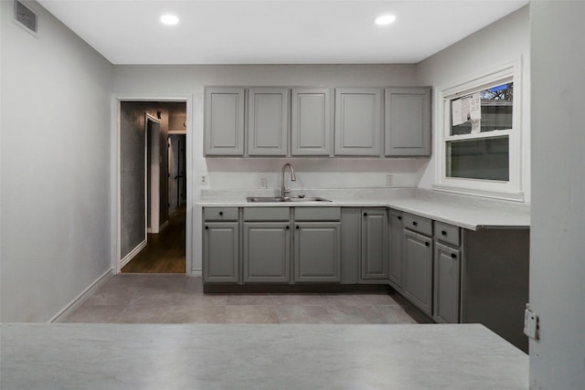 kitchen featuring light countertops, a sink, and gray cabinetry