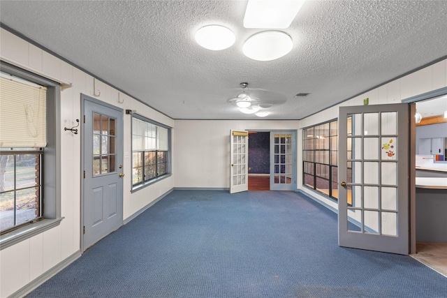 empty room featuring a textured ceiling, visible vents, carpet flooring, and french doors