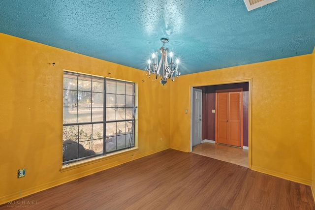 5651 Bretwood Dr, Keithville, LA 71047 - empty room featuring baseboards, a notable chandelier, wood finished floors, and a textured ceiling