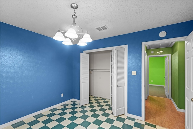 unfurnished bedroom featuring attic access, visible vents, tile patterned floors, a textured ceiling, and a closet