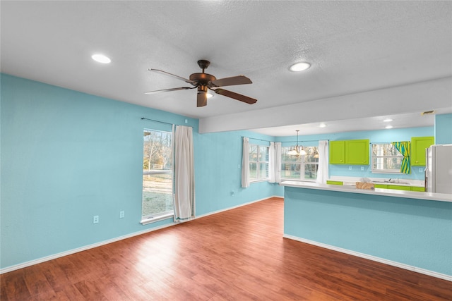 unfurnished living room featuring a textured ceiling, baseboards, wood finished floors, and recessed lighting