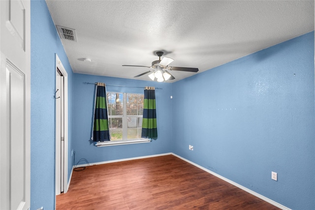 spare room featuring visible vents, a ceiling fan, a textured ceiling, wood finished floors, and baseboards