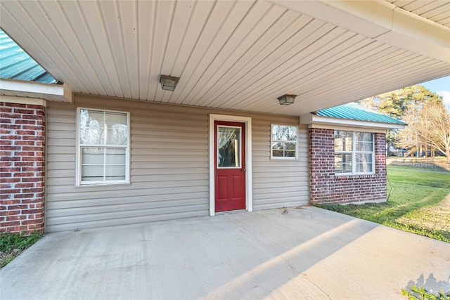 property entrance with a patio, brick siding, and a lawn