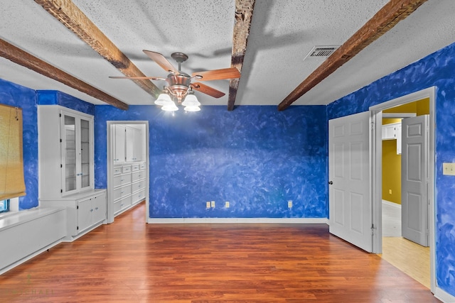 5651 Bretwood Dr, Keithville, LA 71047 - unfurnished bedroom featuring a textured ceiling, wood finished floors, beam ceiling, and visible vents