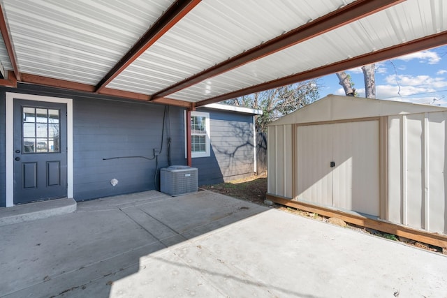 view of patio / terrace with a storage unit, central AC, and an outbuilding