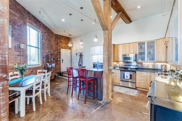 kitchen featuring stainless steel appliances, light brown cabinets, and a towering ceiling