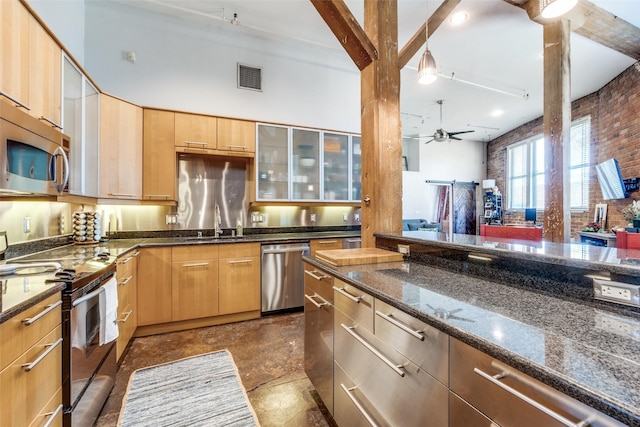 kitchen with visible vents, ceiling fan, appliances with stainless steel finishes, dark stone countertops, and a sink