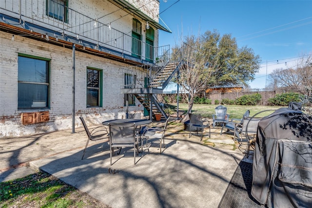 view of patio featuring a fire pit, fence, stairs, and outdoor dining space
