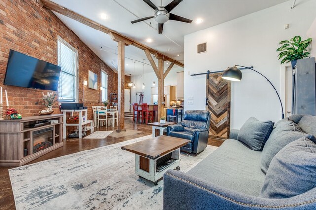 living area featuring a towering ceiling, a barn door, brick wall, ceiling fan, and visible vents