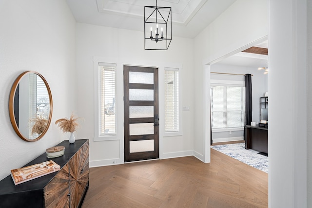 entryway with baseboards, a tray ceiling, and a notable chandelier