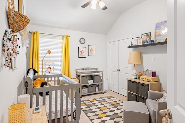 bedroom with ceiling fan, vaulted ceiling, carpet flooring, a nursery area, and a closet