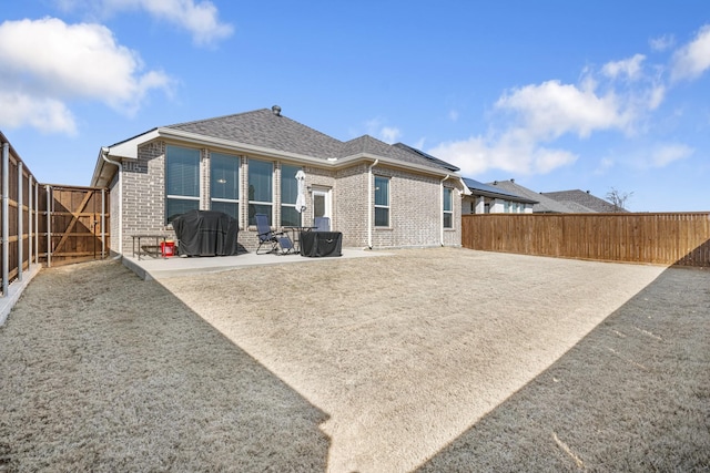 rear view of property with a fenced backyard, a patio, and brick siding